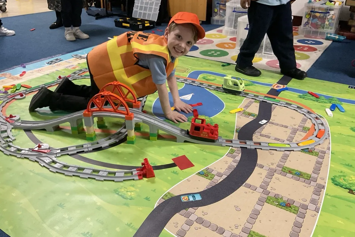 Instructor and child playing with LEGO Duplo trains during an Early Engineers Express workshop