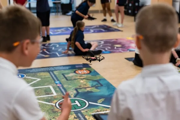 Students flying a drone over a mission mat during a Robotics, Coding & Drones workshop